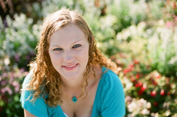 Senior portrait of a young woman in front of a flower bed