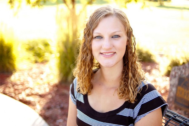 Senior portrait of a young woman on a park bench.