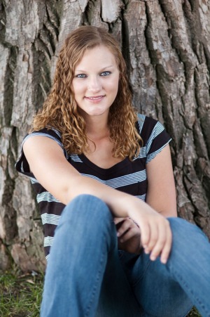 Senior portrait of a young woman sitting in front of a tree