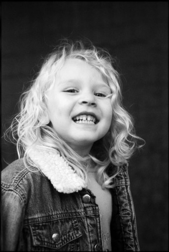 A little girl in a winter jacket smiles at the camera