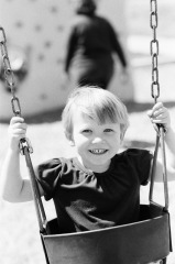 Little girl swinging at the park - distracting background.