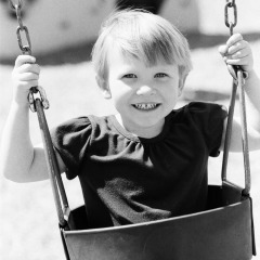 Little girl swinging at the park - cropped