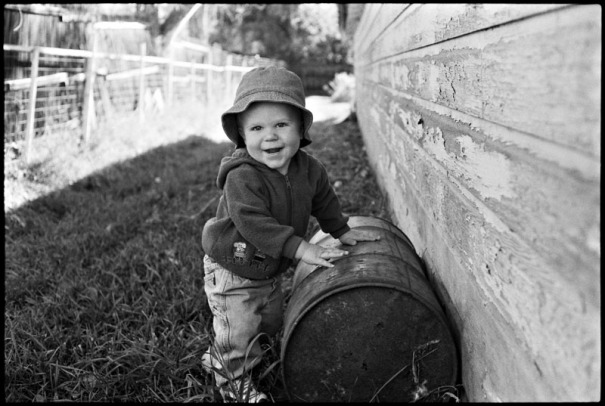 A toddler plays with an old barrel