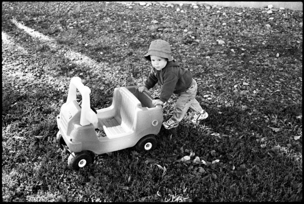 A toddler pushes his toy jeep