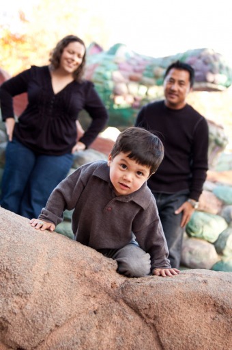 Three year old boy climbing over a wall