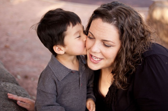 Portrait of a three year old boy kissing his mother
