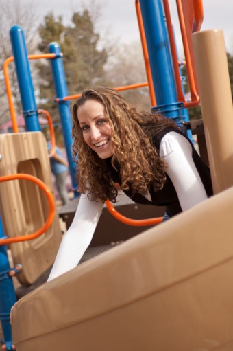 Young woman smiling while climbing on playground equipment