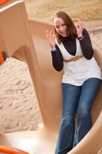 Young woman laughing while going down a slide
