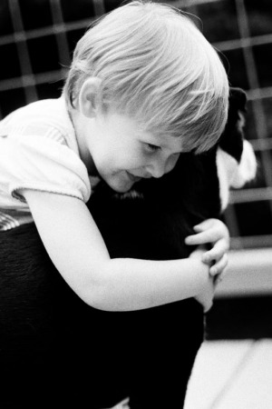 A three year old girl hugs a dog