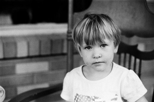 A three year old girl looks into the camera