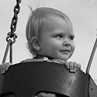 Portrait of a baby girl in a park swing.