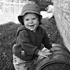 A toddler plays with and old barrel