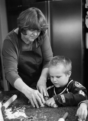 Family portrait of a Grandmother and grandson baking cookies at home in the kitchen. Shot on a medium format camera using black and white film.