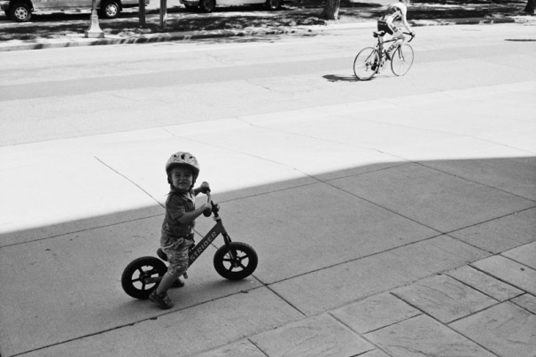 A young boy watches cyclists pass by