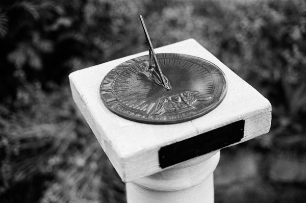 Wet sundial on a white pedestal. Black and white detail photograph from a rainy Boulder, CO wedding.