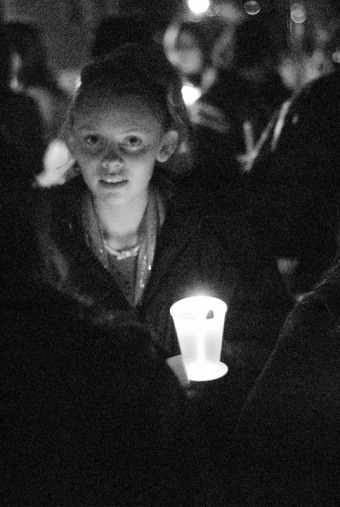 A girl's face is lit up by her candle