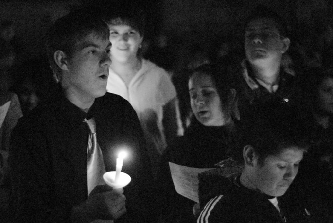 Students hold candles and sing