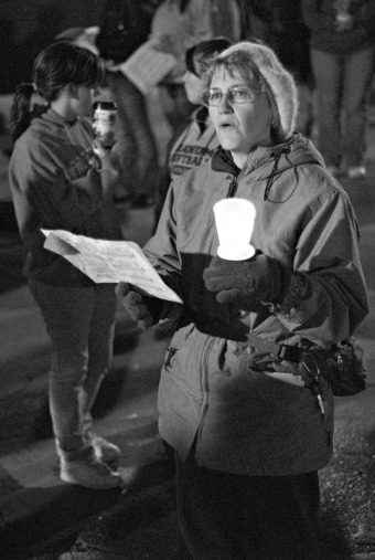 A woman holds a candle and sings