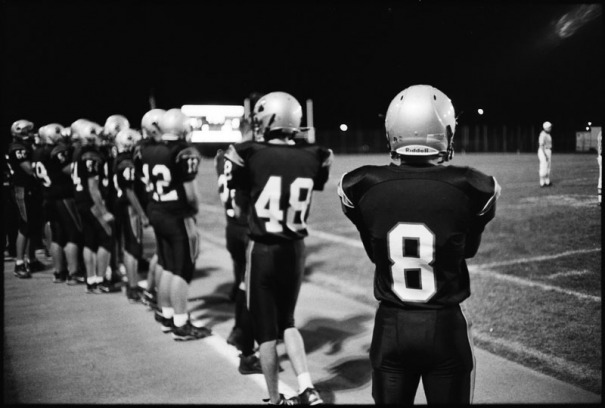 Football players watch from the sidelines
