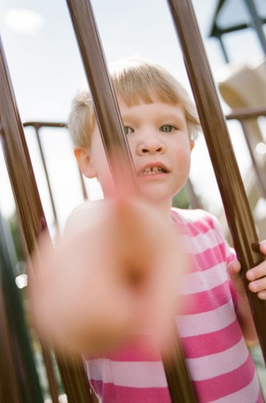 A two year old girl standing on the playground at Nottingham Park in Westminster, CO points in to the camera. Photograph from a documentary portrait session using Fuji 400H film in a Nikon N90s camera.