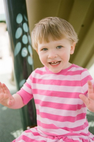 A two year old girl sits for a quick portrait on the playground at Nottingham Park in Westminster, CO. Photograph from a documentary portrait session using Fuji 400H film in a Nikon N90s camera.