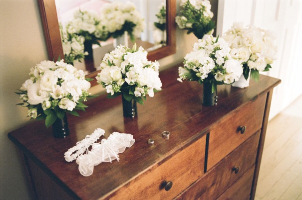 Bouquets, garters, and rings set on a dresser