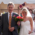 Bride smiles as she is walked down the aisle